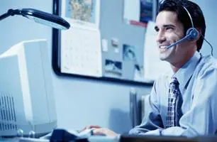 A man sitting at his computer with a headset on.